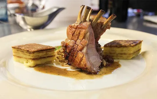 A plated lamb dish with sauce.