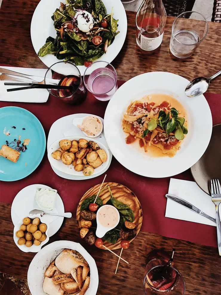 Plates of food and drinks on a red tablecloth.