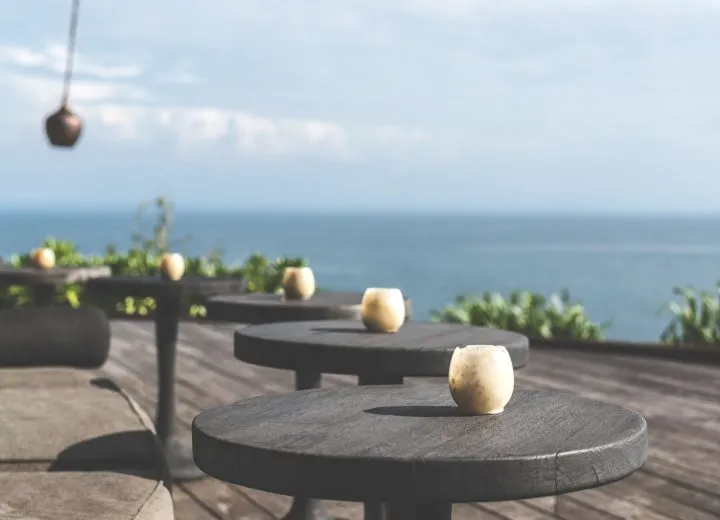 Candles on round tables on a terrace facing the sea.