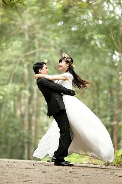 A bride and groom dancing among tall trees.